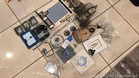 Photo showing all coastal bathroom decor items laid out on tiled floor including mirrors, photo frames, towel hardware, ceramic decor and shower curtain rings