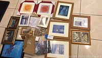 Overview of assorted framed and unframed wall art and wooden decor laid out on floor