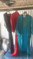 Three silk robes hanging on a railing, black, red, and turquoise colors visible