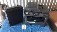 Photo of Brother MFC7860DW printer and black paper shredder on a blue cloth.