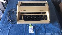 Full view of the Olympia electric typewriter showing beige body and attached power cord.
