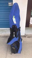 Blue golf bag standing upright with cover on top, fully zipped