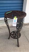 Full side view of cast iron outdoor table showing round top and leg design with grapevine pattern.