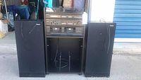 Photo of full Panasonic stereo system showing the main receiver unit with attached wires and two matching stereo speakers on each side.