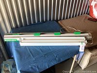 Long white fluorescent shop light fixture on table with blue cloth, showing length and plugs.