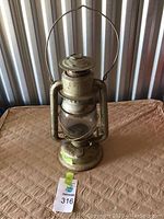 Front view of a vintage Beacon railway lantern showing the glass globe, metal frame, and handle.