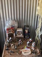 Overview photo showing multiple Christmas village ceramic houses and figurines arranged on a table along with boxed items and holiday accessories.