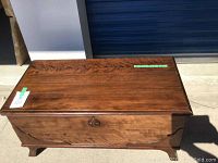 Top and front view of vintage wooden cedar chest showing wood grain, size labels, and decorative front medallion