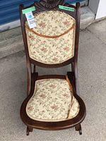 Photo showing the chair with floral fabric cushions on the backrest and seat, with visible wear and fraying on the cushions.