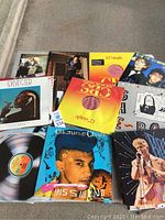 Full display of 25 various vinyl records with colorful covers visible on sidewalk