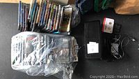 Overview of large DVDs collection, some stacked and some wrapped in plastic, with power cords visible
