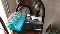 Complete lot assortment on chair seat and back: bird cage, bird swing, battery clock, desk globe, Philips Hue starter kit box.