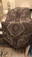 Dark paisley patterned tassel table runner displayed folded.