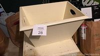 Wooden bucket with round cut-out handles in cream paint, placed on floor.