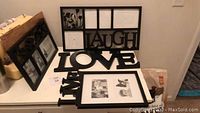 Set of black photo frames showing 'LAUGH', 'LOVE', and 'LIVE' frames with various photo slots, placed on white surface.