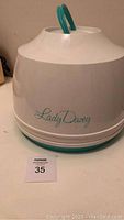 Front view of the hair dryer dome showing Lady Dizzy branding, white plastic with turquoise handle and base.