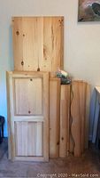 Unfinished wood panels including doors and flat boards stacked upright