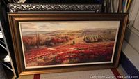 Full view of wide framed landscape painting showing a vivid poppy field and distant hills.