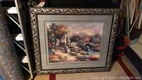 Full view of large framed landscape wall art with glass pane showing a nature scene with columns and watermill.