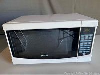 Front view of white RCA microwave with black glass door and digital keypad