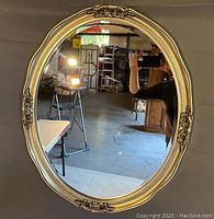 Full view of the large oval wall mirror showing the beveled glass and the entire pewter finish ornate frame.
