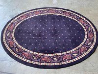 Full view of oval area rug showing eggplant background with paisley border pattern and small flower motifs.