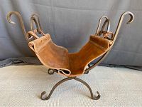 Front angle view showing leather sling cradle and iron scrollwork legs