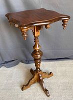 Front view of small wooden occasional table showing scalloped top, turned pedestal and tripod base.