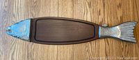 Top-down view of the entire wooden fish-shaped serving platter with metal head and tail attached.
