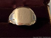 Front view of gold signet ring showing well worn surface and partial engraving on face.