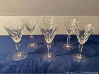 Front view showing all six Waterford Sheila cut claret wine goblets arranged in two rows on a blue surface with white background.