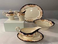 Photo showing all seven pieces in the set: large platter, serving bowl, gravy boat with underplate, cream jug, sugar bowl with lid, and relish dish.