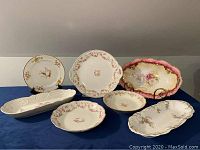 Photo showing all seven assorted vintage European china serving pieces, each with floral decorations and gold accents.