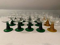 Front view showing full set of 12 green stemmed glasses and 3 gold stemmed glasses arranged in rows