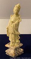Front view of pale green stone figure standing on mottled marble base