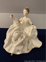 Front view of the Royal Doulton "My Love" figurine showing detailed face, hand holding a pink flower, and full dress with gold accents.