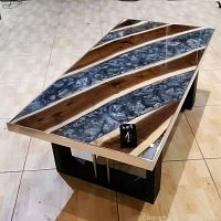 Angled front view of coffee table showing live-edge walnut and metallic gray epoxy resin top with metal trim edging and black base
