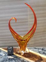 Front view of red-orange flame-shaped art glass centerpiece vase with clear glass base and upward curved flames.