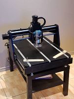 Front-angle view of entire CNC machine on stand, showing T-track table and mounted router