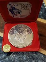 Reverse of medallion showing heraldic eagle with shield, inscriptions 'United States of America' and '1 LB. Fine Silver', red velvet interior and label