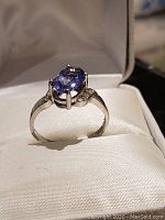 Front view of ring on cushion showing oval tanzanite center and overall setting