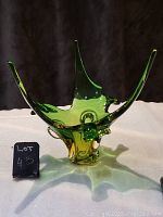 Front view of the green and amber glass art centerpiece with three high pointed extensions, showing shape and color gradient.