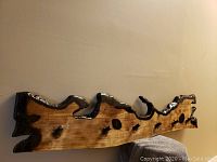 Front angled view of the live edge epoxy coat hanger showing wood grain, black epoxy coated edges and wooden pegs for hanging.