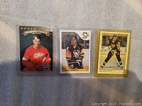 Three hockey cards in protective sleeves, featuring Gordie Howe, Mario Lemieux, and Jaromir Jagr.