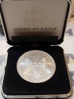 Photo of the silver American Eagle coin with eagle and shield design in protective case.