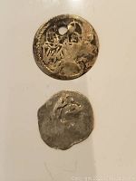 Top and bottom views of two Ottoman silver coins. The top coin is round with Arabic inscriptions and a hole near the edge. The bottom coin is irregularly shaped and worn.
