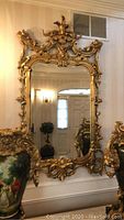 Full front view of ornate gilt mirror hanging on wall