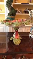 Full view of Majolica bird bath on table showing overall shape, leaf designs, and pedestal base.