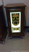 Front view of dark brown wood cabinet with illuminated Golden Nugget sign and metal claw feet