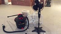 Overview of Shop-Vac, dehumidifier, pedestal fan and two box fans on concrete floor